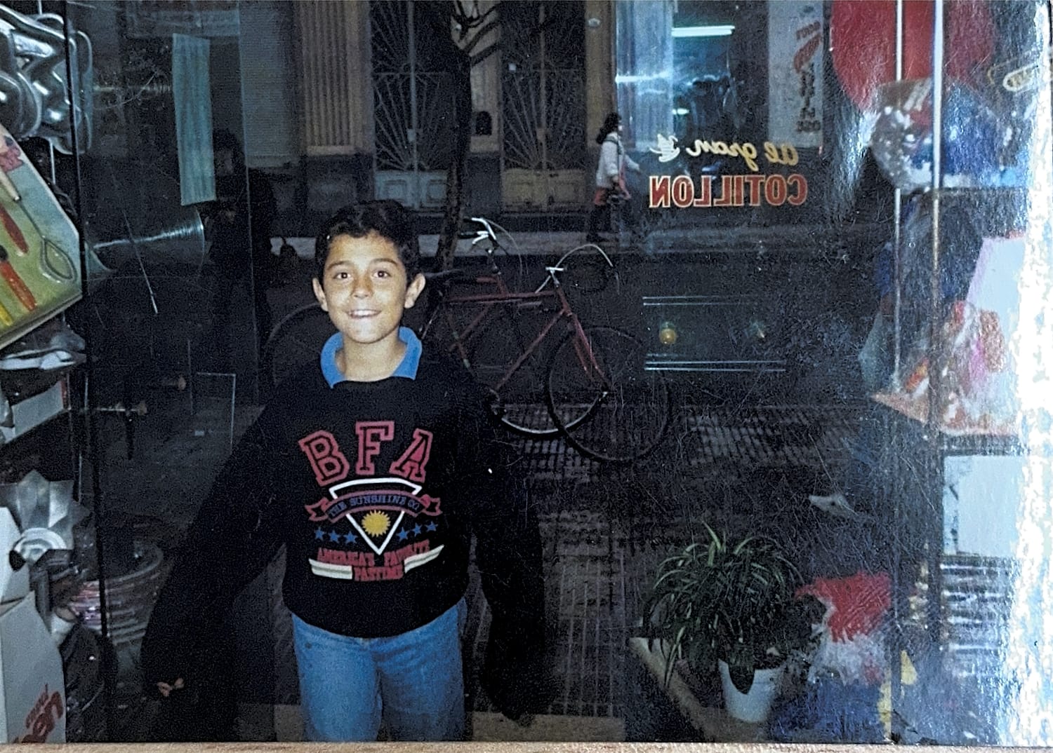 Un niño en la puerta del local con el cartel de cotillón